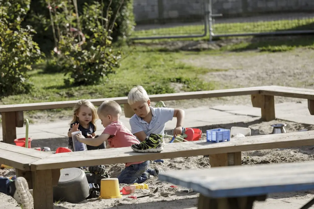 Tre børn leger koncentreret i sandkassen.